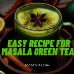 A cup of masala green tea having lemon and spices around it