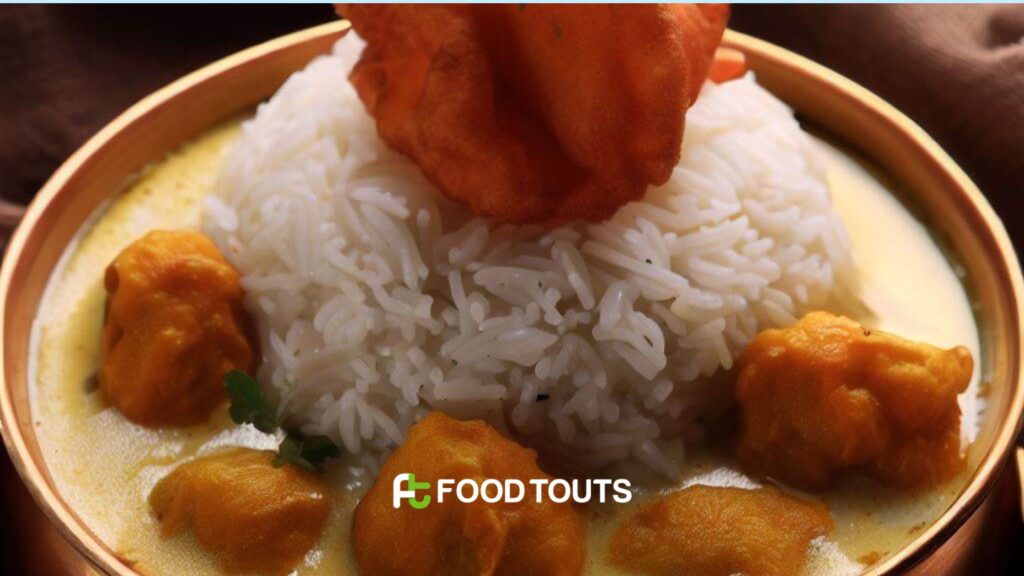 A brass bowl of Kadhi Chawal with a beautiful representation of pakoras