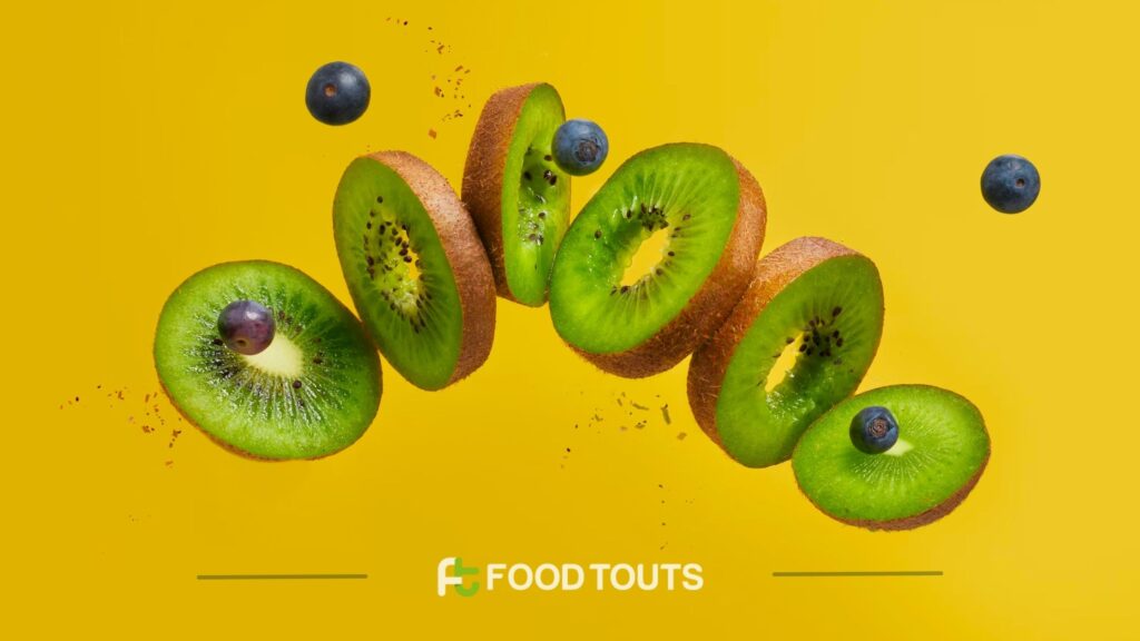 A photo of cut Kiwi fruit with grapes flying